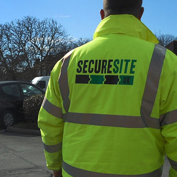 a secure site security guard in a high vis jacket overlooking a car park