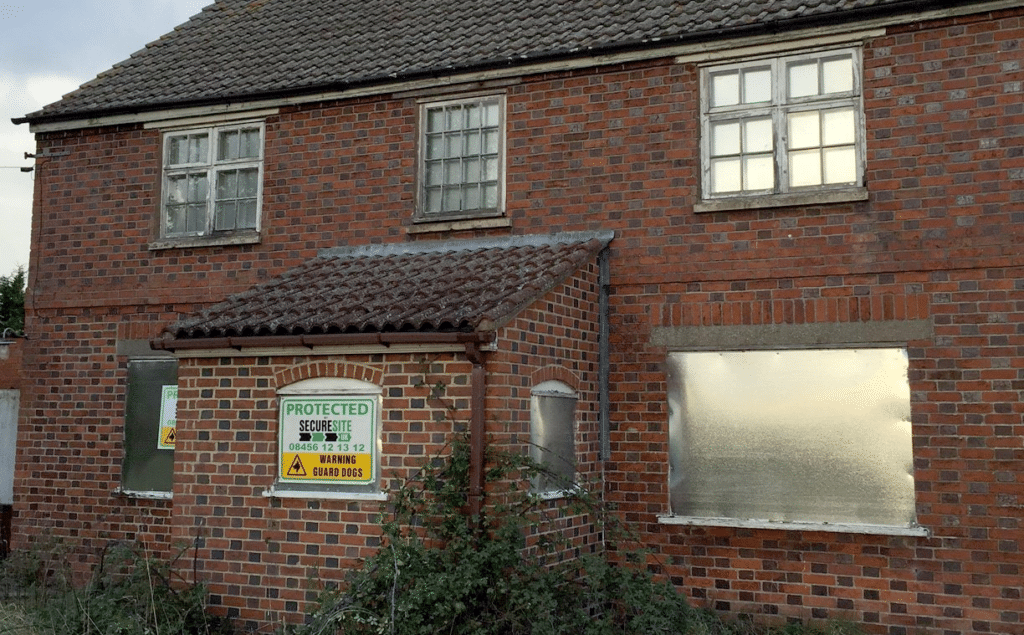 Vacant property with steel security screens covering all windows with warning signs affixed
