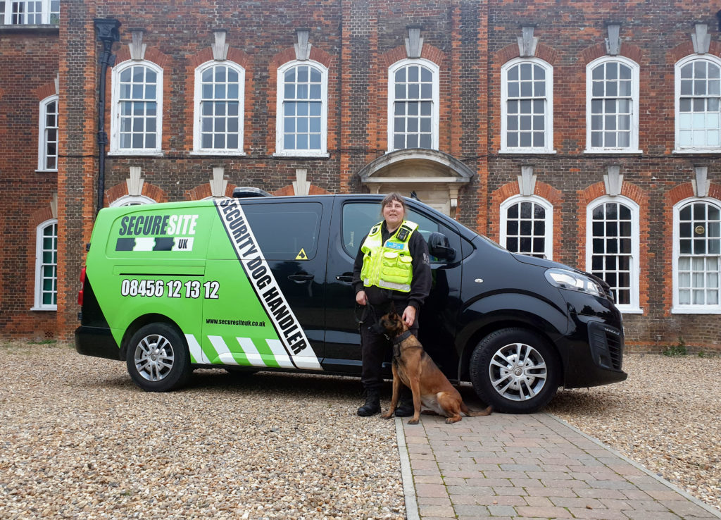 Security dog handler and dog infront of a Secure Site UK branded van and a large building